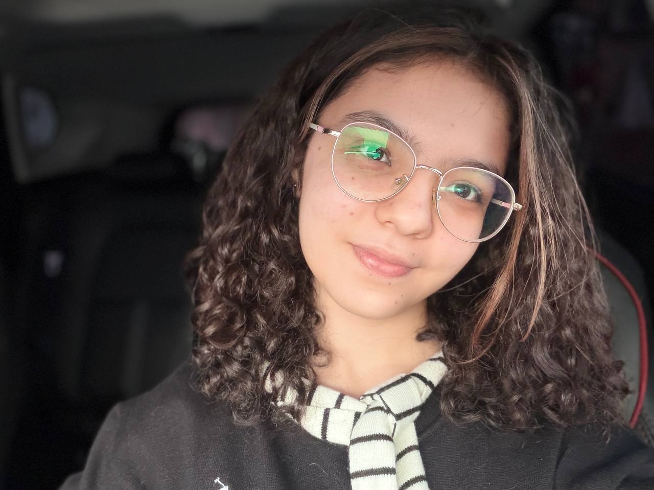 Marjona smiling, wearing glasses